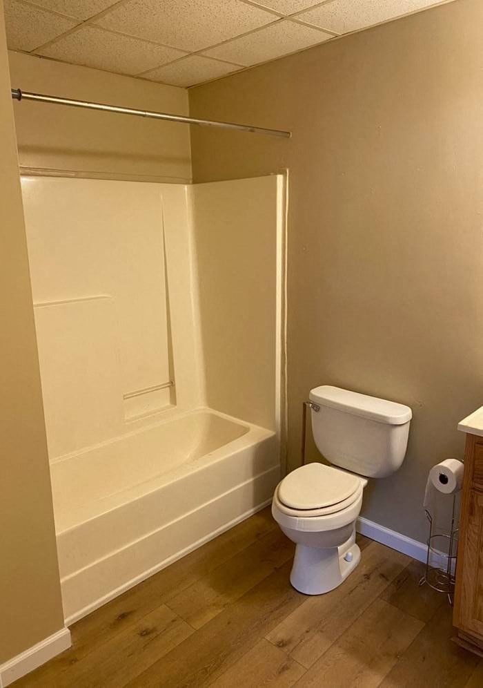 A white toilet sits in a bathroom next to a toilet paper roll.