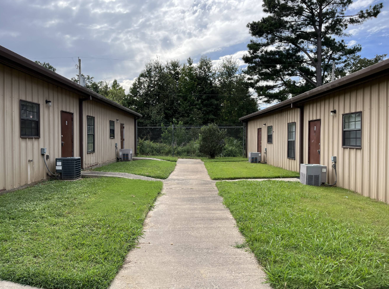 A concrete walkway leads between two rows of identical buildings.