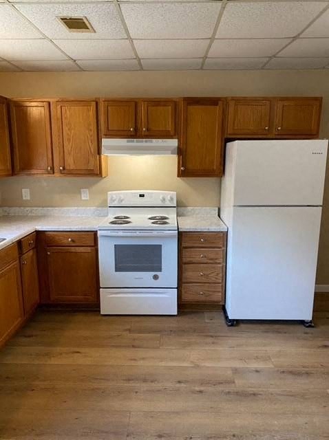 A white refrigerator sits next to a stove in a kitchen.