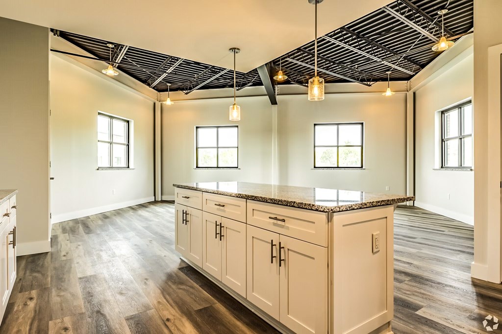 A kitchen with white cabinets and a wooden floor.