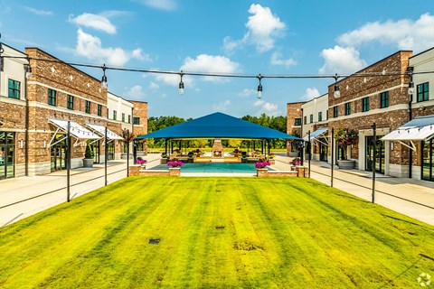 A large grassy area with a pool and buildings on either side.