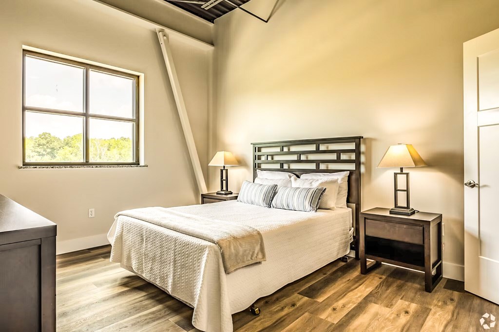 A bedroom with a large bed and two lamps.