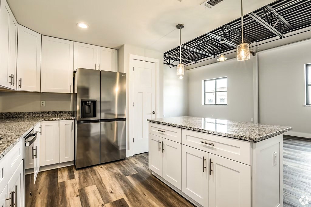 A kitchen with white cabinets and a granite countertop.