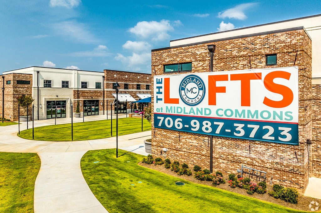 A building with a sign that says "The Lofts at Midland Commons" and a phone number.
