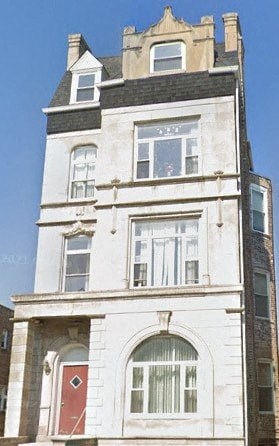 A white building with a red door and windows.