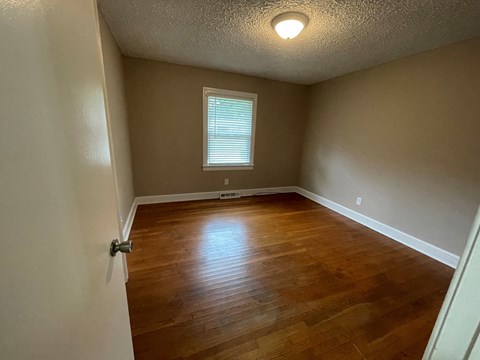 an empty living room with wood floors and a window