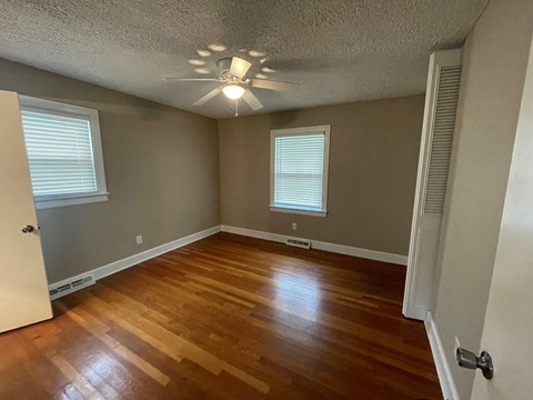 an empty living room with wooden floors and a ceiling fan