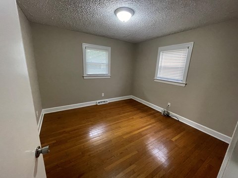 a living room with a hard wood floor and two windows
