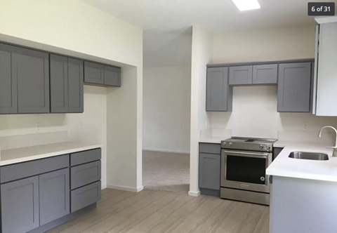A kitchen with grey cabinets and a white counter top.