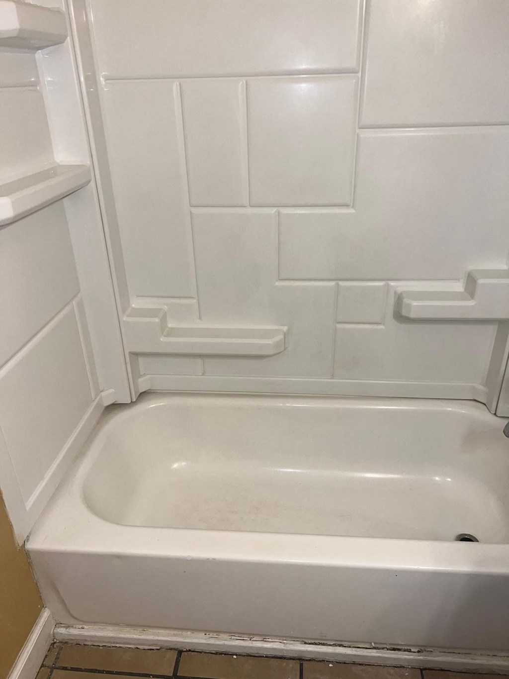 a bathroom with a white tub and a white tiled wall