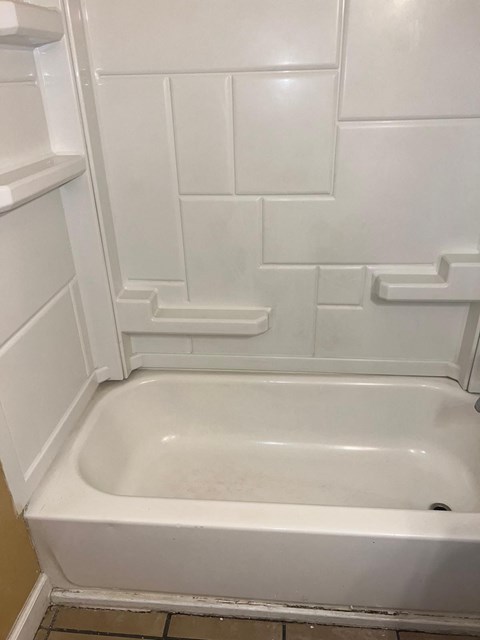 a bathroom with a white tub and a white tiled wall