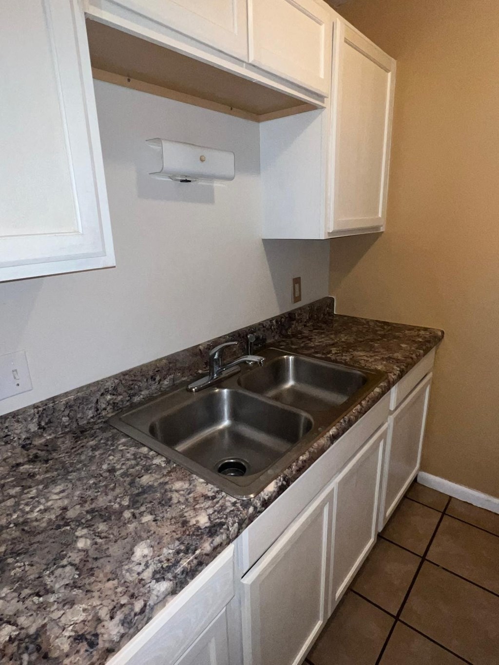 the kitchen has a stainless steel sink and white cabinets
