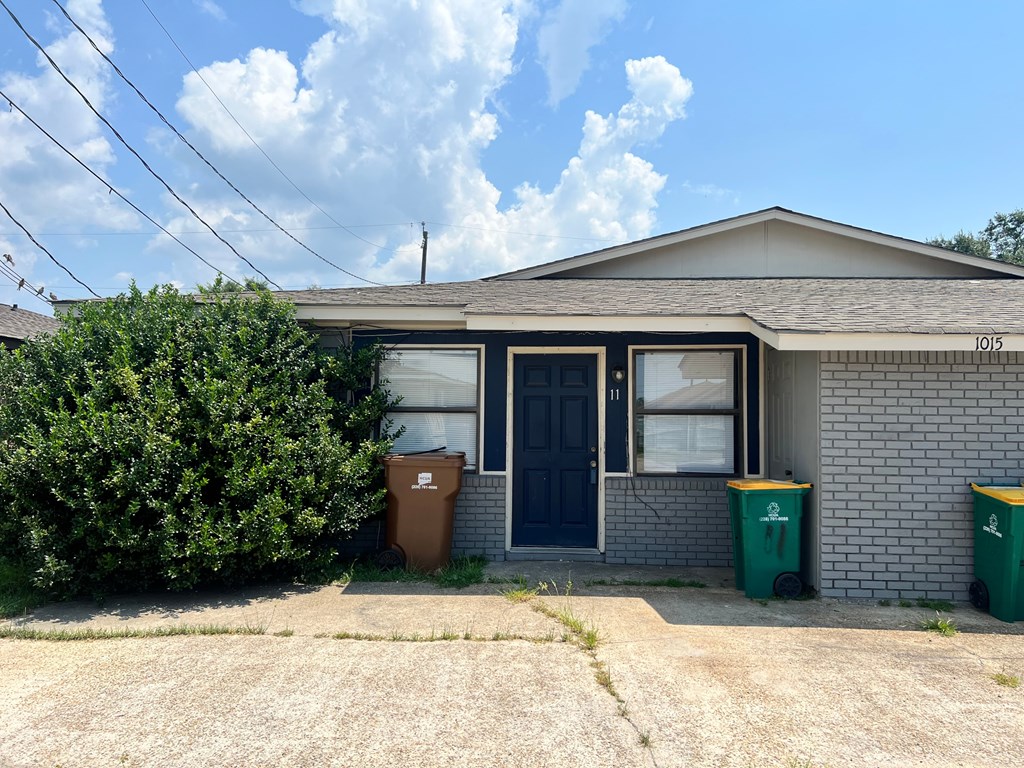 a house with a blue door and trash cans in front of it