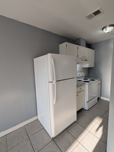 A white refrigerator is in a kitchen with a stove top oven.