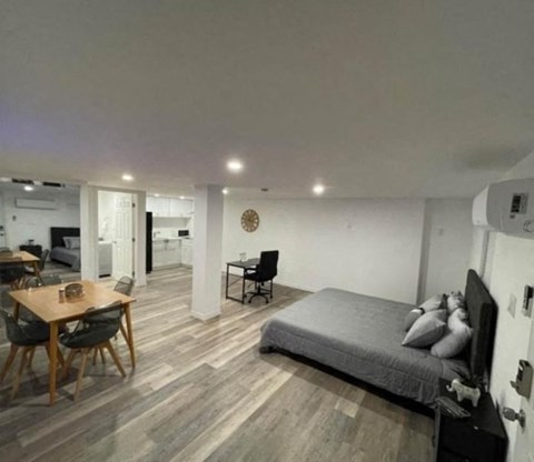 A bedroom with a bed, a table and chairs, and a dining area.