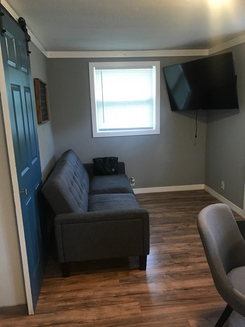 A living room with a grey couch and a blue door.