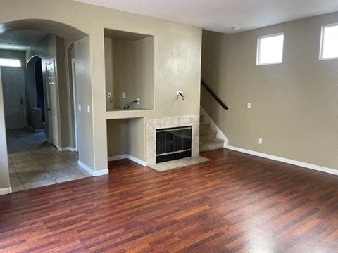 A living room with a fireplace and wood flooring.