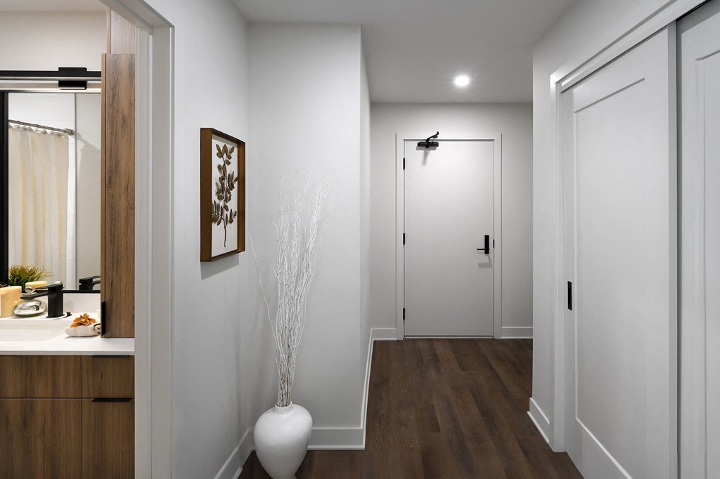 a long hallway with a white door and a vase on the floor