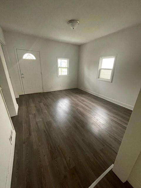 an empty living room with hardwood floors and white walls