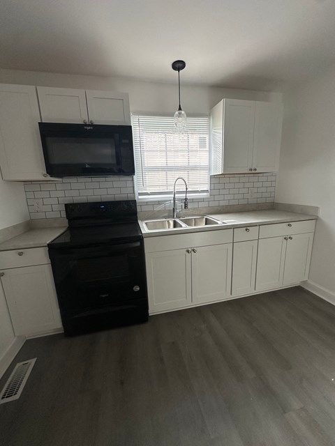 an empty kitchen with white cabinets and black appliances