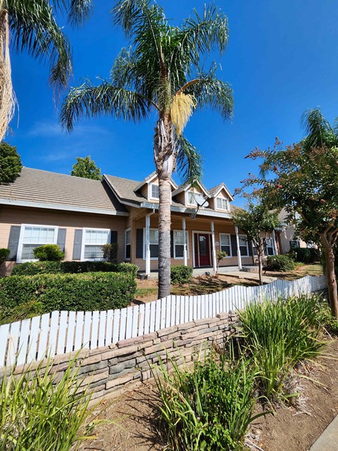 a house with a white fence and a palm tree in front of it