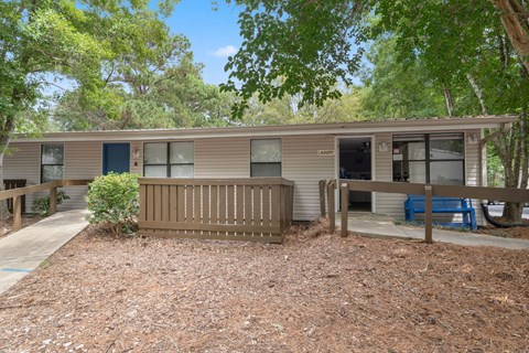 A building with a brown roof and a blue door is surrounded by trees.