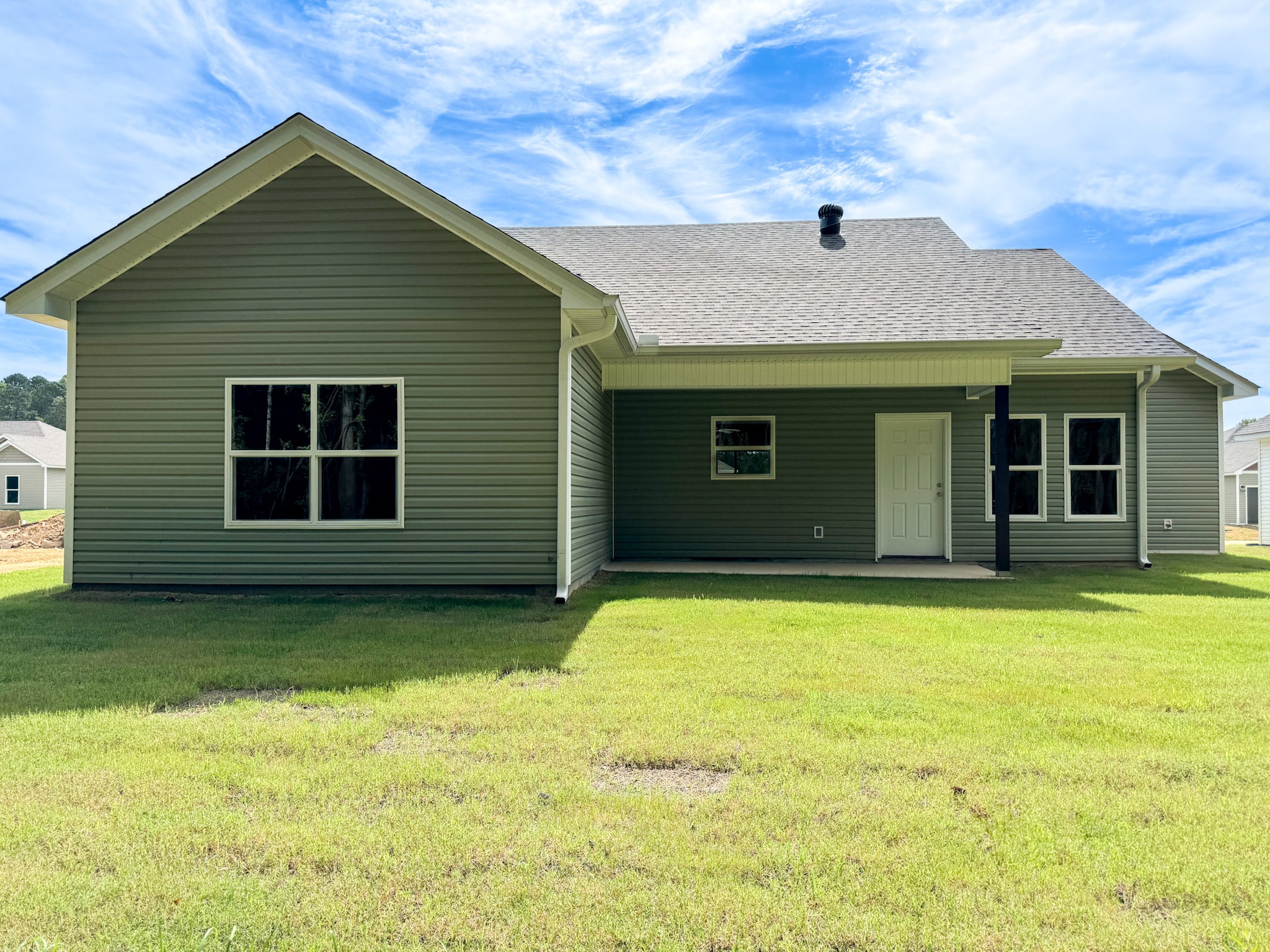 a green house with a lawn and a blue sky