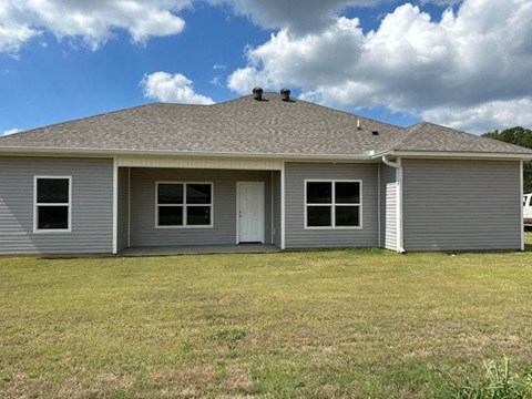 a gray house with a yard and a cloudy sky