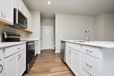 A kitchen with white cabinets and black appliances.
