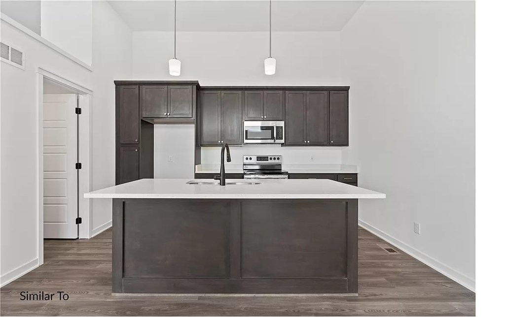 A modern kitchen with dark brown cabinets and white countertops.