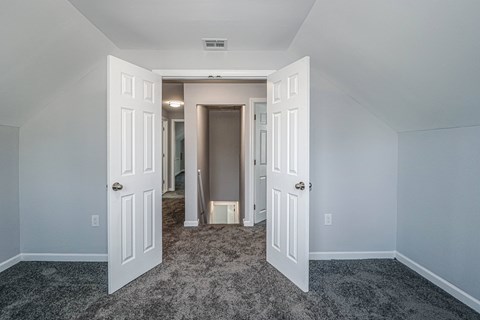 A room with a carpeted floor and two open doors.