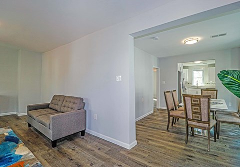 A living room with a grey couch and wooden floors.