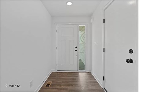 A white door is in a hallway with wood floors.