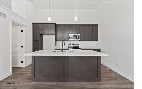 A modern kitchen with dark brown cabinets and white countertops.