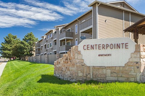 A stone wall with a sign that says Centerpointe Apartments.