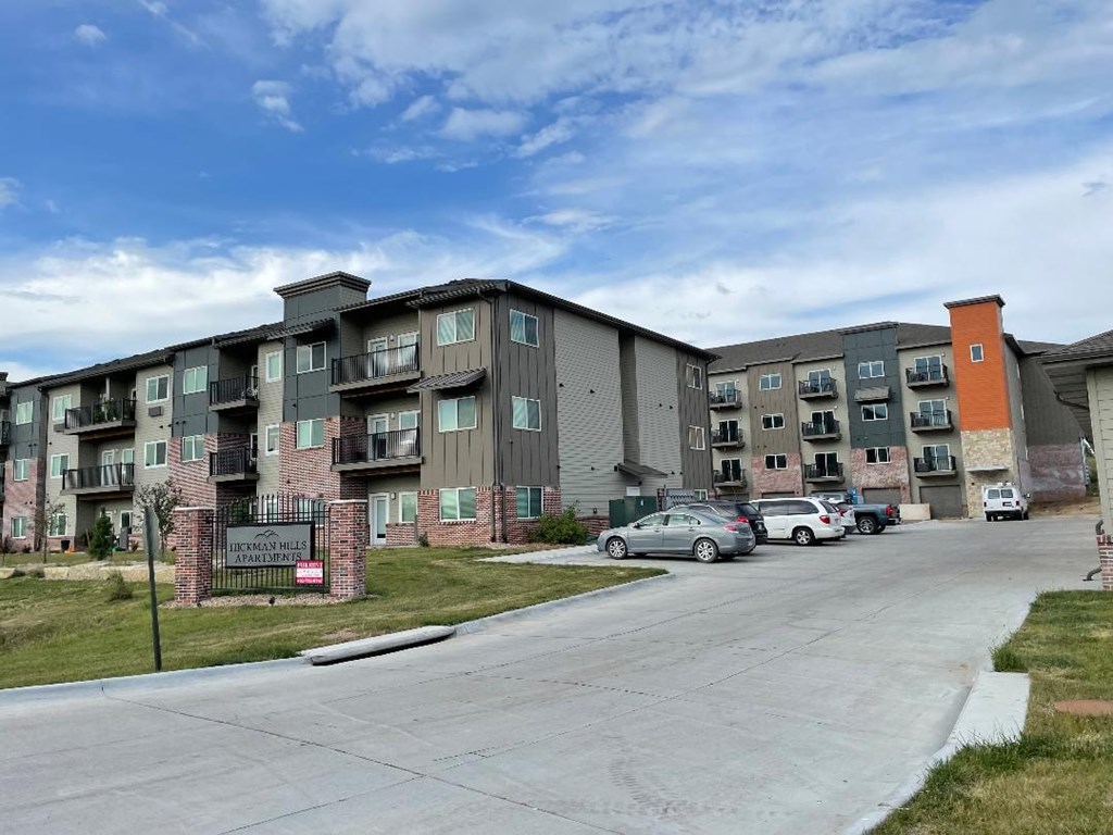 a street view of an apartment building with cars parked in front