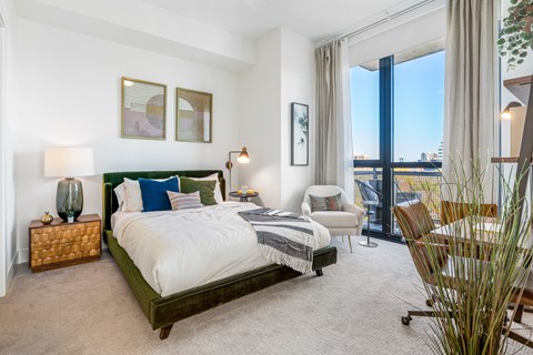 a bedroom with a bed and a chair and a balcony