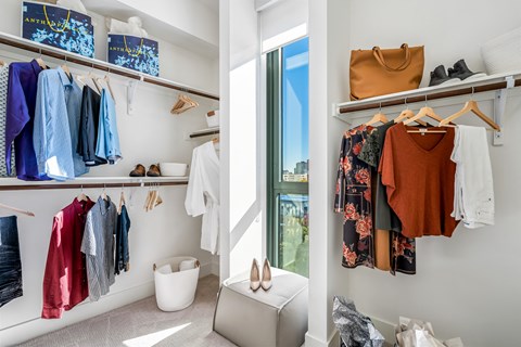 a closet with shelves and a window and a closet filled with clothes