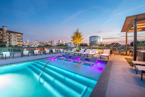 a pool on the roof of a building with a city in the background
