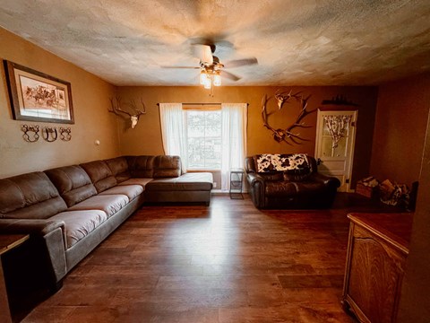 a living room with leather furniture and a ceiling fan