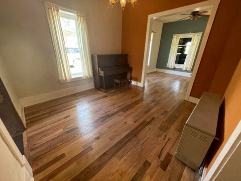 a living room with a hard wood floor and a piano