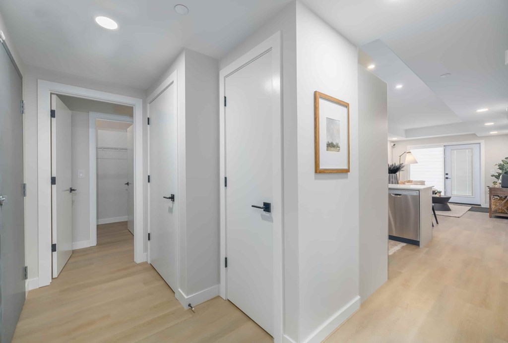 A hallway with white doors and a framed picture on the wall.