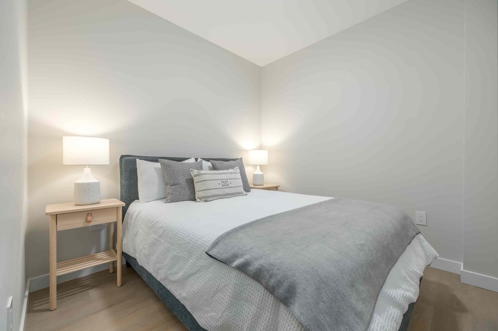 A bedroom with a bed, nightstand, and two lamps.