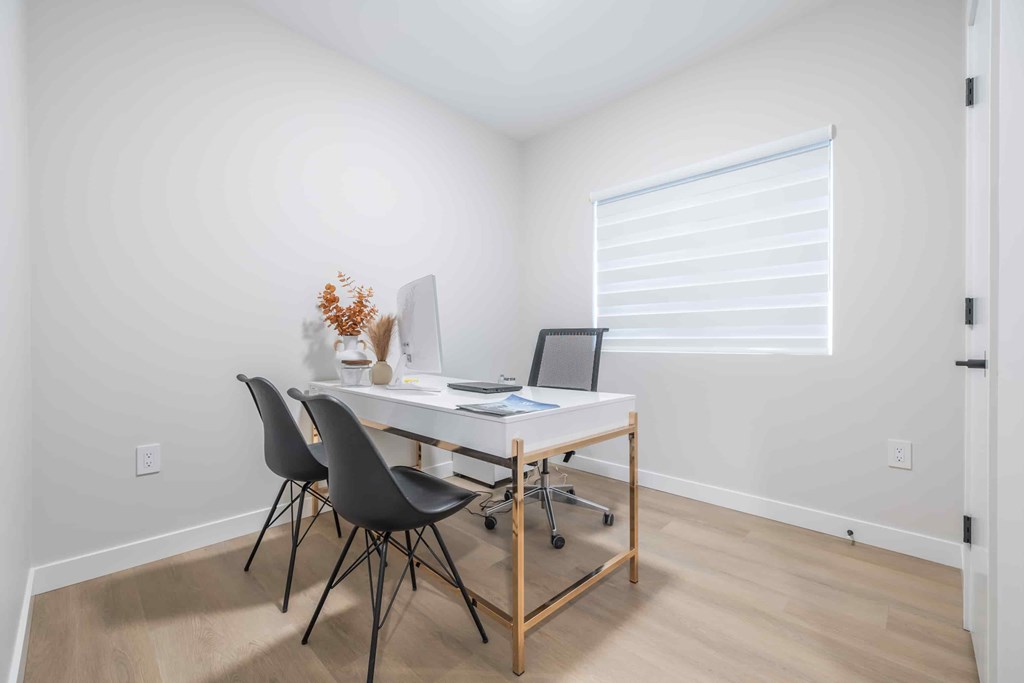 A white desk with a laptop and a vase of flowers on it.