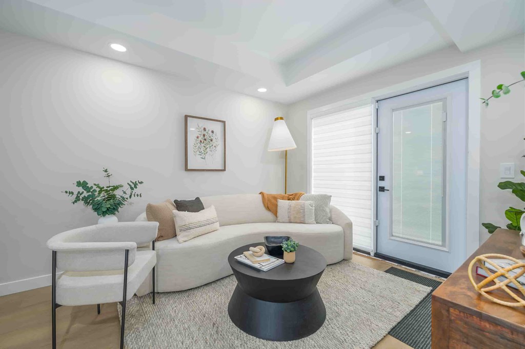 A living room with a white couch, a black coffee table, and a white chair.