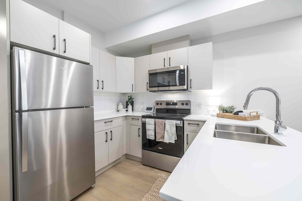 A modern kitchen with a stainless steel refrigerator and a microwave above the stove.