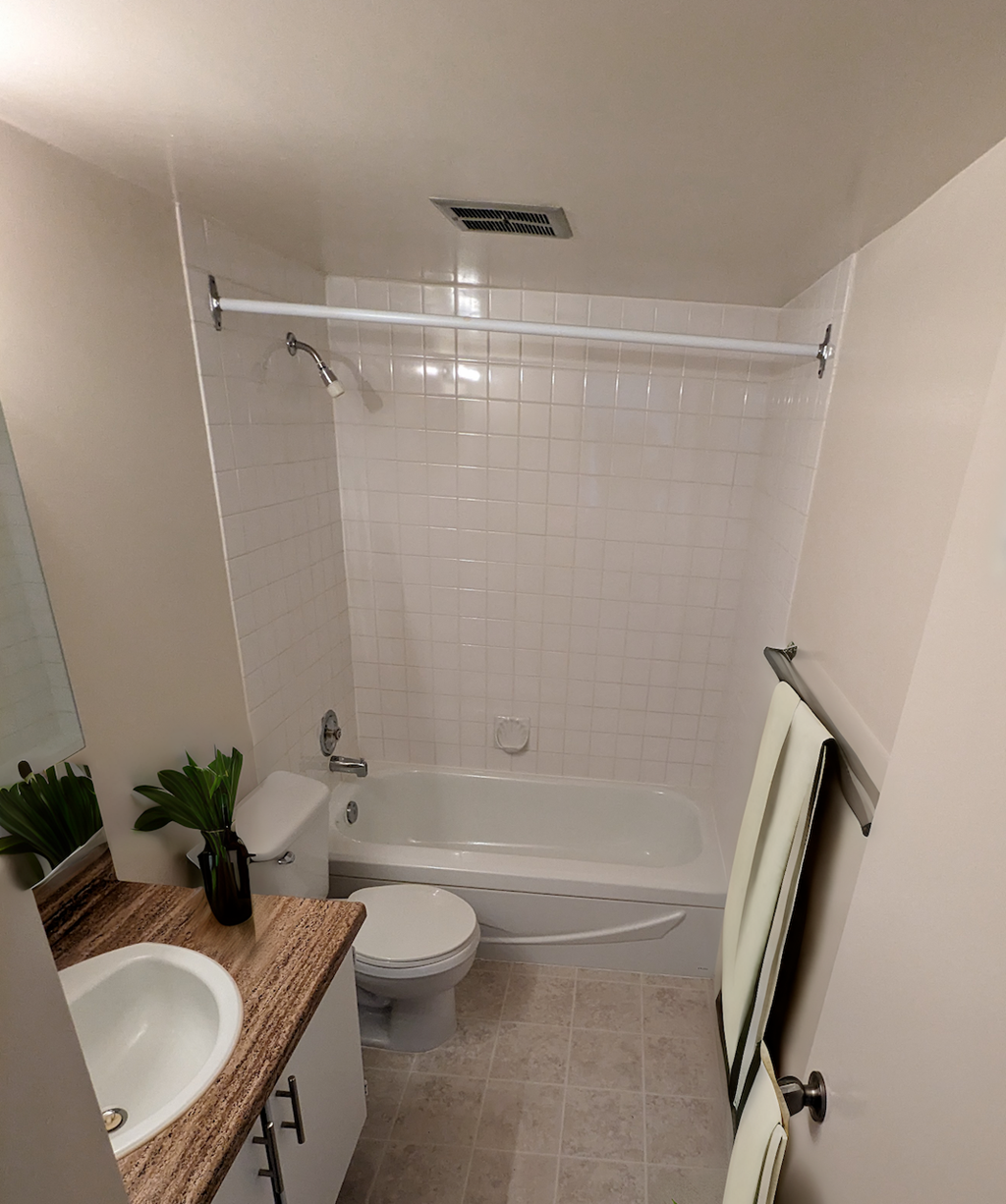 A white tiled bathroom with a toilet, sink, and bathtub.