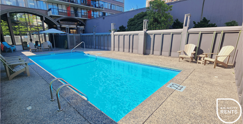 A swimming pool surrounded by a concrete floor and a metal fence.