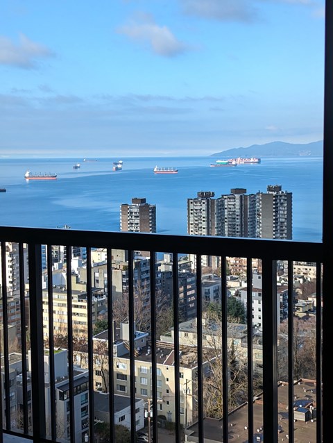 A view from a balcony looking out at a cityscape and ships in the water.
