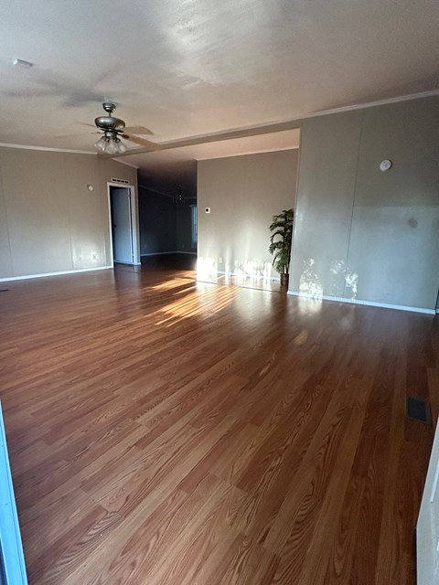 an empty living room with wooden floors and a ceiling fan
